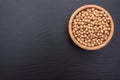 Peeled chickpeas lies in a wooden cup on a stony black board, black background, space for text