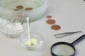 Peeled copper coins lie on the table surface. Corroded coins are lying nearby in a container with phosphoric acid. Sulfuric