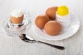 Peeled egg on egg stand, spoon, plate with salt shaker, boiled eggs on wooden table Royalty Free Stock Photo