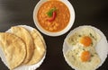 Peeled fava beans with chili pepper in white bowl pita bread and fried eggs on dark wooden background