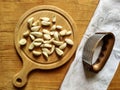 Peeled garlic cloves on chopping board, next to garlic chopper and gray linen towel on old wooden background. Concept of cooking Royalty Free Stock Photo