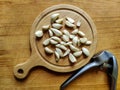 Peeled garlic cloves on chopping board next to garlic chopper on old wooden background. Concept of cooking Royalty Free Stock Photo