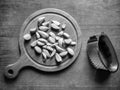 Peeled garlic cloves on chopping board, next to garlic chopper (press) on old wooden background. Concept of cooking Royalty Free Stock Photo