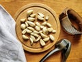 Peeled garlic cloves on chopping board, next to garlic choppers and gray linen towel on old wooden background. Concept of cooking Royalty Free Stock Photo