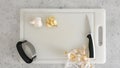 Peeled garlic, garlic press, and kitchen knife close-up on a white plastic cutting board, flat lay Royalty Free Stock Photo