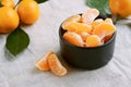 Peeled mandarine in black bowl on linen tablecloth