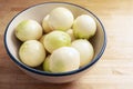 Peeled organic onions in a bowl on a wooden table, cooking at home during the coronavirus pandemic, selected focus