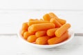 Peeled pieces of carrot in plate on white wooden table Royalty Free Stock Photo