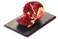 Peeled pomegranate fruit on black slate stone plate. Red juicy seeds inside.