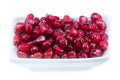 Peeled pomegranate seeds in a cup along with a fraction of fresh pomegranate isolated on white