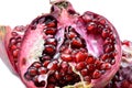 Peeled pomegranate seeds in a cup along with a fraction of fresh pomegranate isolated on white