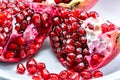 peeled pomegranate seeds in a cup along with a fraction of fresh pomegranate isolated on white