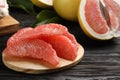 Peeled pomelo slices on black wooden table, closeup