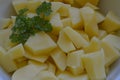 Peeled potatoes with parsley in white bowl