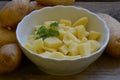 Peeled potatoes with parsley in white bowl on wooden background Royalty Free Stock Photo