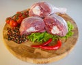 Peeled raw chicken thigh on wooden round board on white background. Royalty Free Stock Photo