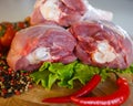 Peeled raw chicken thigh on wooden round board on white background. Royalty Free Stock Photo