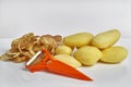 Peeled raw potatoes, peeling potatoes and peeler on a white background close-up