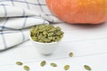 Peeled raw pumpkin seeds on a wooden spoon and in small ceramic bowl