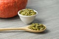Peeled raw pumpkin seeds on a wooden spoon and in small ceramic bowl