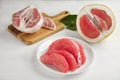 Peeled red pomelo slices on white wooden table