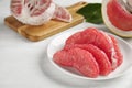 Peeled red pomelo slices on white wooden table