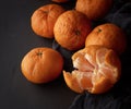 Peeled ripe orange mandarin and a bunch of unpeeled round whole fruits