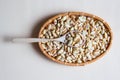 Peeled salted peanuts in wicker basket and wooden spoon on beige background Royalty Free Stock Photo