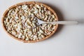 Peeled salted peanuts in wicker basket and wooden spoon on beige Royalty Free Stock Photo