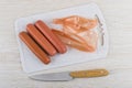 Peeled sausages, polyethylene shell on cutting board, kitchen knife Royalty Free Stock Photo