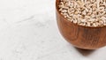 Peeled sunflower seeds in small wooden cup, placed on white stone like board space for text left side, closeup detail Royalty Free Stock Photo