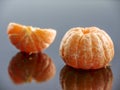 Peeled tangerine on a black mirror surface