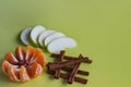 Peeled tangerine in the form of a flower with peanuts, sliced green apple slices and folded brown cinnamon sticks on a yellow Royalty Free Stock Photo