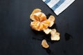 Peeled tangerine lies on the board. There are drops of juice and tangerine peel around.