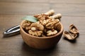 Peeled walnuts in bowl and nutcracker on wooden table, closeup Royalty Free Stock Photo