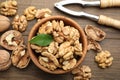Peeled walnuts in bowl and nutcracker on wooden table, flat lay Royalty Free Stock Photo