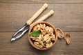Peeled walnuts in bowl and nutcracker on wooden table, flat lay Royalty Free Stock Photo