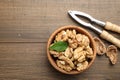 Peeled walnuts in bowl and nutcracker on wooden table, flat lay. Space for text Royalty Free Stock Photo