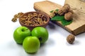 Peeled walnuts in wooden bowl, green apples, firewood