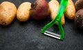 Peeler and homemade vegetables. Black background.