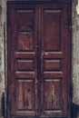 Peeling brown wooden door. Dilapidated wooden grunge door with cracked maroon paint. Threadbare dark red door.