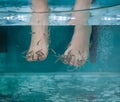 Peeling with fish. Girl enjoying medicinal procedure and receiving massage with small fishes. Foot massage with fish Royalty Free Stock Photo