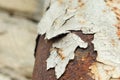 Peeling old paint from a metal pipe that has corroded. Chemical transformations in building materials that lead to