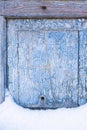 Peeling paint on the old door in the snow. A pattern of rustic blue grunge material. Abstract background. Royalty Free Stock Photo