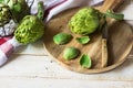 Peeling and preparing fresh artichokes, scattered leaves, cutting board, knife, linen towel on kitchen table Royalty Free Stock Photo