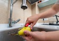 Peeling a ripe pear under running water in a modern kitchen sink for hygiene Royalty Free Stock Photo