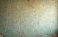 Peeling turquoise wallpaper with visible floral pattern. Wall shows cracks and plaster damage revealing aged texture. Aged Royalty Free Stock Photo