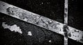 Peeling white paint forms diagonal stripes on a textured black asphalt surface.