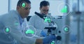 Peering techs white coats blue gloves using scope handling slide in lab with floating green icons Royalty Free Stock Photo