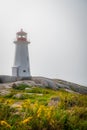 Peggy's Cove lighthouse on a foggy day with yellow flowers, Nova Scotia, Canada Royalty Free Stock Photo